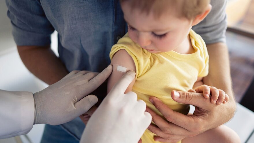 A bandage is placed on a child's arm after receiving a vaccination. State health officials have expanded eligibility for the measles, mumps, and rubella (MMR) vaccine, allowing infants as young as 6 months in areas with active spread to receive an elective dose.