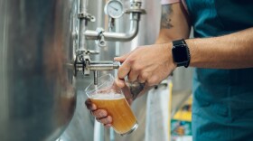 Portrait of a bearded man working in a brewery and checking quality of the craft beer. Brewery owner tasting beer from the best bach. Cropped shot of a man filling a glass of beer on a tap.