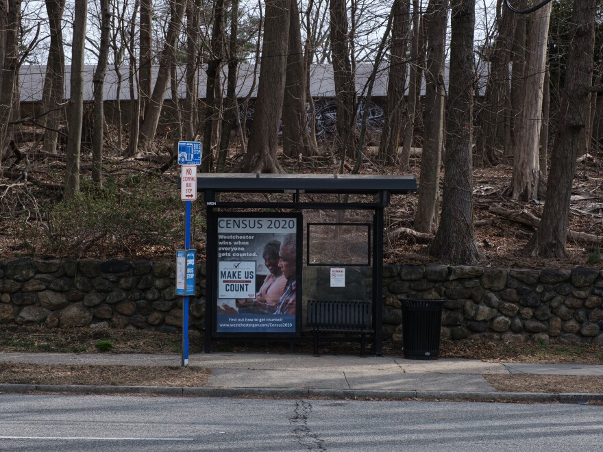 A bus stop with a poster promoting the 2020 census sits empty in New Rochelle, N.Y., a New York City suburb where National Guard members were sent to try to slow the spread of the coronavirus outbreak.