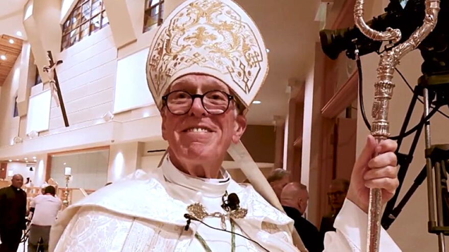 older man catholic bishop clothing holding staff and wearing a miter