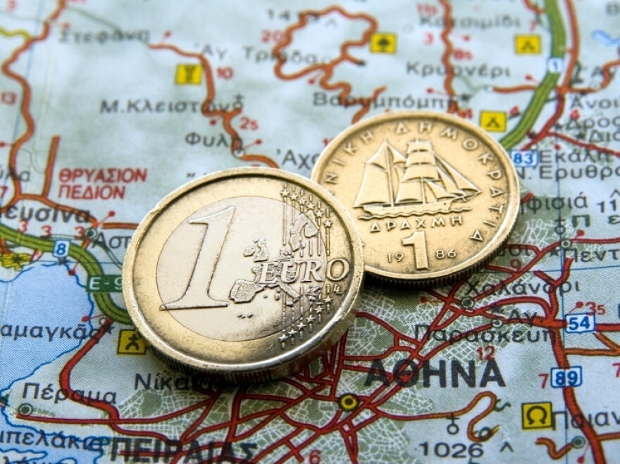 A euro coin and an old Greek drachma rest on a map of Greece. Some observers have predicted a Greek exit from the eurozone.