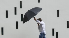 A man walks in the rain along a street in Austin, Texas, Nov. 11, 2022.
