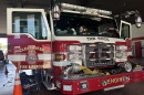 red-and-white Clearwater Fire & Rescue fire truck parked inside a fire station with its front doors open. Firefighting gear lays on the ground around.