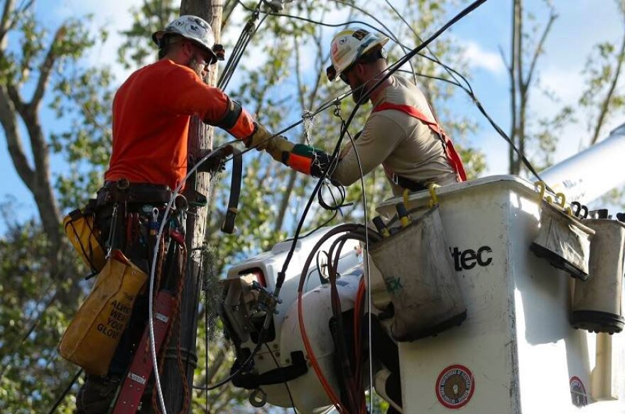 FirstEnergy utility workes repair a electric line damaged by a tree limb.