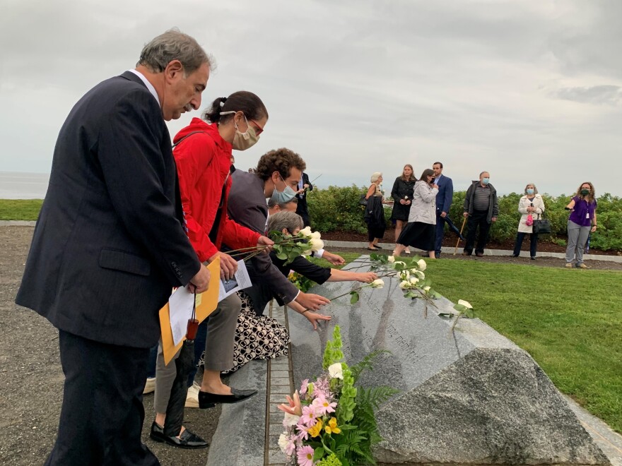 Attendees lay white roses on the 9/11 memorial at Sherwood Island State Park in Westport Thursday night. It's a yearly tradition to read the names of Connecticut's lost and lay the flowers.