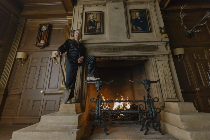 Tom Cruise poses with a shovel in front of a large fireplace.