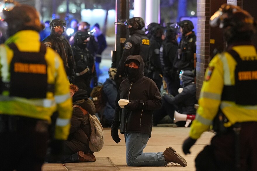 Protesters sit on the ground after police declared an unlawful assembly during a noise demonstration outside the Graduate by Hilton Minneapolis hotel on Wednesday, Jan. 28, 2026, in Minneapolis.