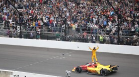 Alex Palou stands on his vehicle to the cheers of the crowd after winning the 109th running of the Indianapolis 500.