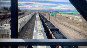 Looking down from a bridge at a coal train with cars filled with coal.