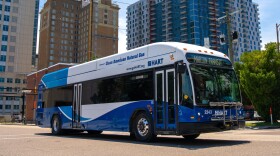 A large city bus in front city building 
