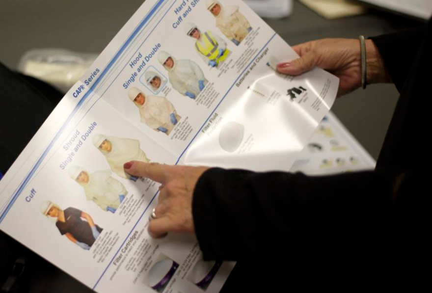 An attendee looks through different types of hoods during a training session on personal protective equipment in Houston.