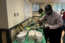 The father of a family of 8 grabbing paper plates and plastic spoons to give to his children. Staff at Jewish Family Service of Western Massachusetts, a resettlement agency in the region, organized a potluck for the family who recently arrived from a refugee camp in Zimbabwe after 20 years of surviving there.