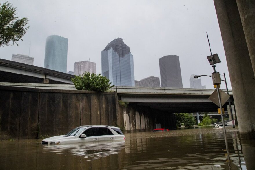 Two cars are nearly covered by flood waters under an interstate bridge in Houston.