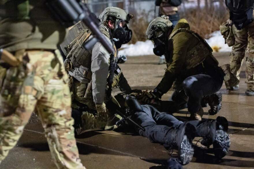 Federal immigration officers detain a demonstrator outside Bishop Whipple Federal Building after tear gas was deployed Monday, Jan. 12, 2026, in Minneapolis. (Jen Golbeck/AP)