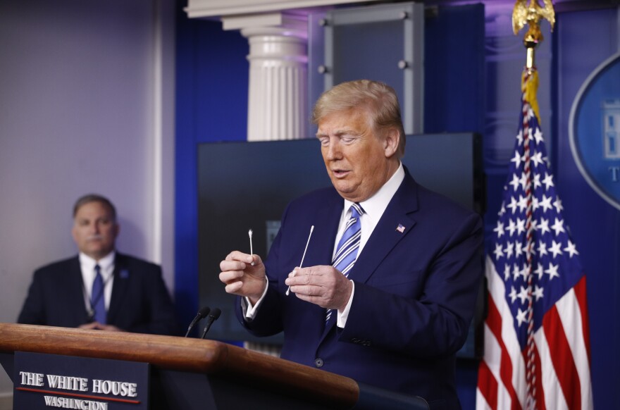 President Trump compares a cotton swab (left) to a swab that could be used in coronavirus testing during a briefing on April 19. Two days prior, Trump erroneously said cotton swabs could be used for coronavirus testing.