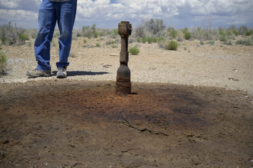 Austin stands next to a leaking oil well in the Rattlesnake Oil Field. (Jerry Redfern)