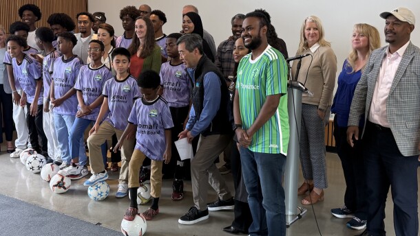 Seattle Mayor Katie Wilson poses with adults and kids kicking a soccer ball.