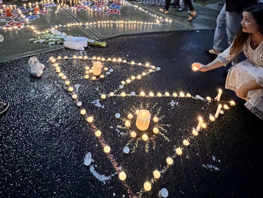 A candle arranged in the shape of the Nepali flag at a vigil for Rasuwa flood victims outside an Albany temple. 