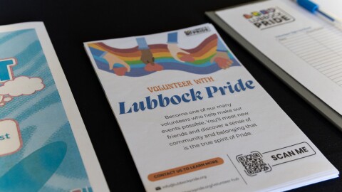 A photo of various pamphlets and sign-ups on the LubbockPRIDE table at the resource fair. Centered is a handout that says 'Volunteer with Lubbock Pride: Become one of our many volunteers who help make our events possible. You'll meet new friends and discover a sense of community and belonging that is the true spirit of Pride.