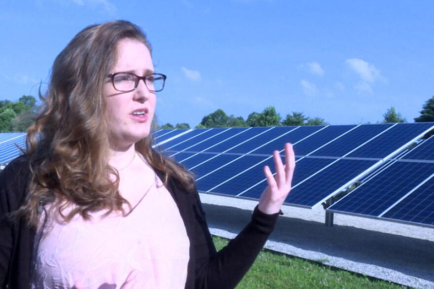 Indiana University student Savannah Rodrigue stands in front of a solar array next to a water booster station in Bloomington which helps to offset some of the station's energy use.
