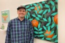 John G. Slaby stands beside one of his paintings at a gallery show.