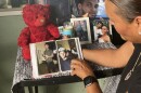  Arlene Garcia flipping through a photo book of pictures of her son, Kevin Johnson, in front of a memorial to him on the front porch of her home.