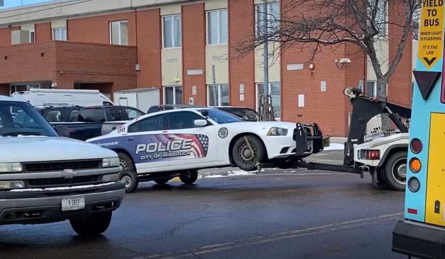 A tow truck tows a patrol car after a Missoula Police officer reported that the car's back window had been shot out during a traffic stop near the Missoula Courthouse Feb. 12, 2020.