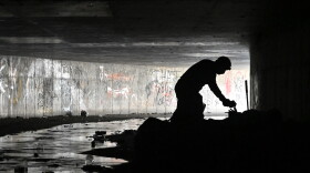 FILE - In this Dec. 5, 2020, file photo, Dave Marlon of CrossRoads of Southern Nevada, offers some items to an individual during an outreach in the underground tunnels to provide counseling, food and water to the homeless living beneath the city in Las Vegas.