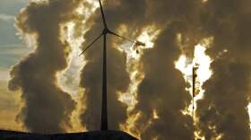 A wind turbine is pictured in the in front of a steaming coal power plant in Gelsenkirchen, Germany. (Martin Meissner/AP)