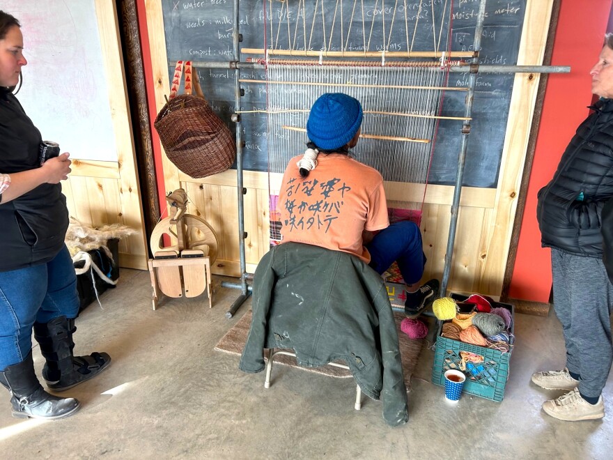 Tyrrell Tapaha, an apprentice weaver, weaves a textile of sheep wool on a loom.