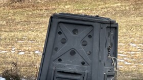 Crooked, broke-down compost bin with snow in foreground, field in background