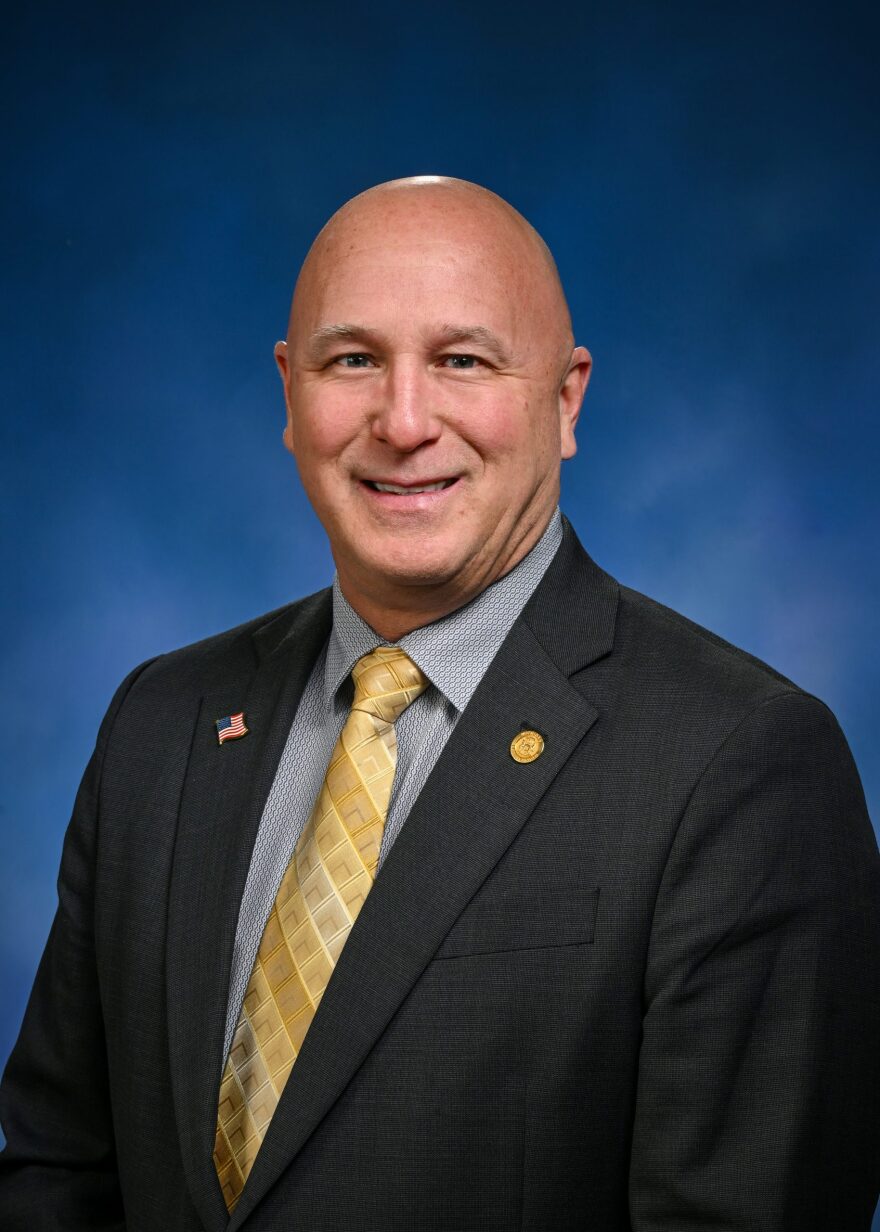A man in a suit poses for a photo.