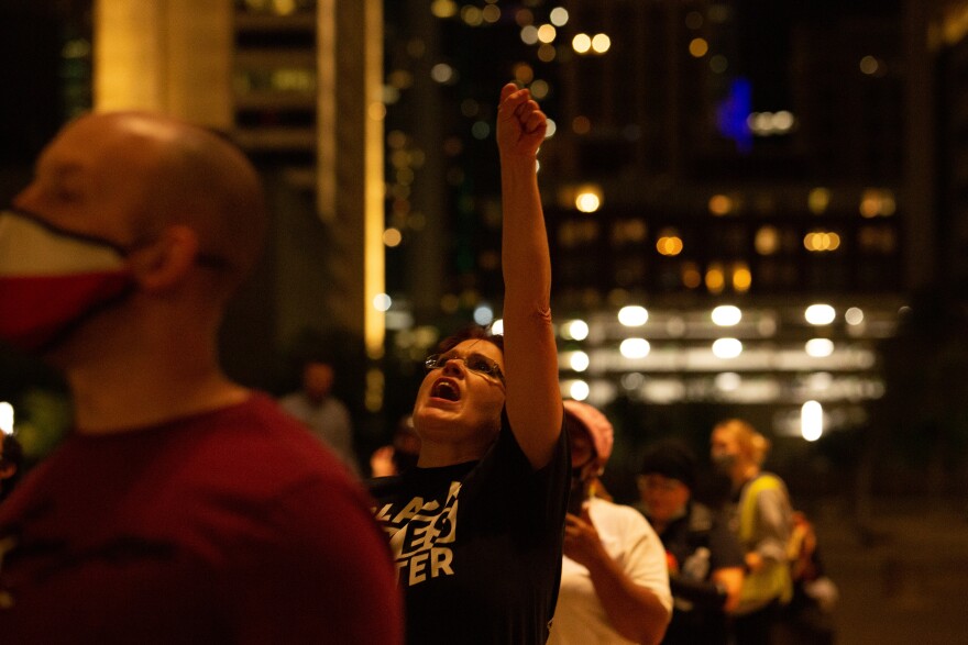 Photo of Deborah Spanier standing in a crowd wearing a Black Lives Matter t-shirt shouting with her fist in the air.