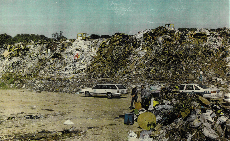 People walk by the illegal landfill known as the Deepwood dump.
