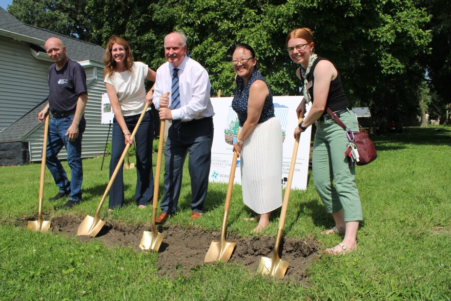 Three women and two men hold gold shovels to break ground on a new rain garden at 506 Gridley Street in Bloomington.