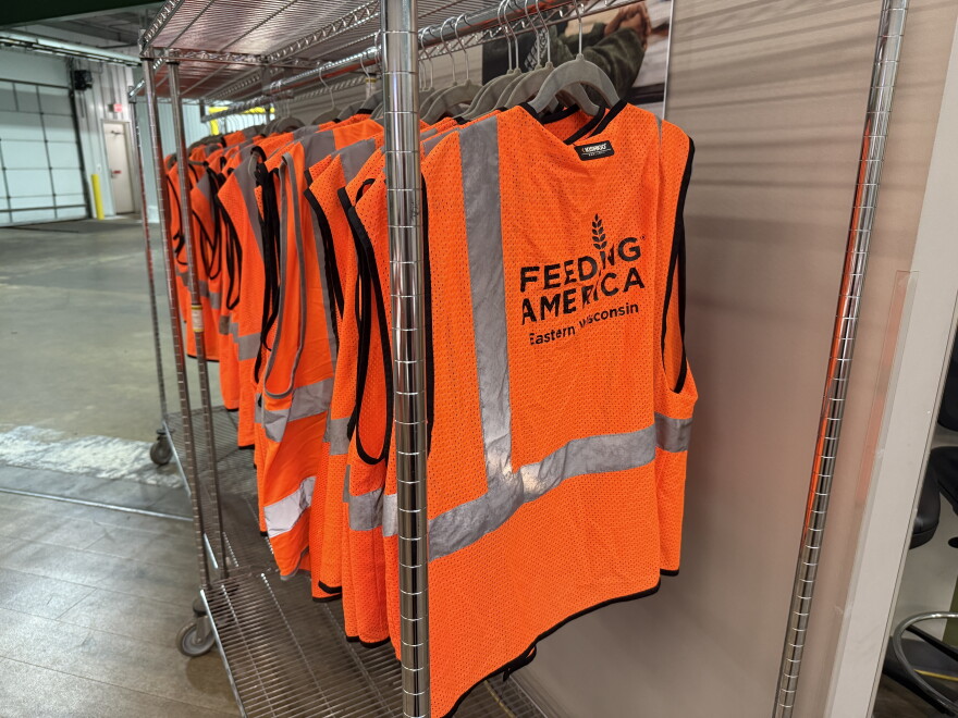 Neon orange Feeding America vests hung up on rack