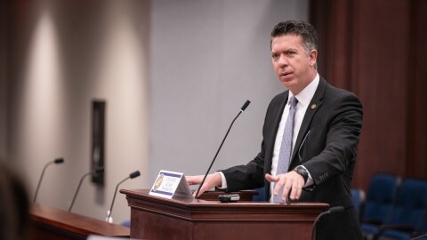 Man in suit speaks into podium