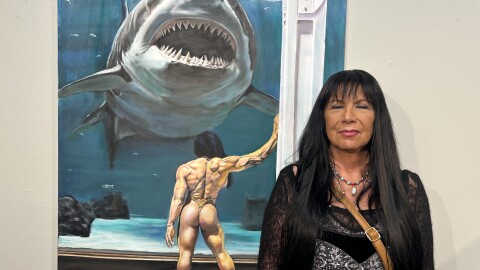 Artist Gloria Mandala poses for a portrait next to her painting, "The Conversation"