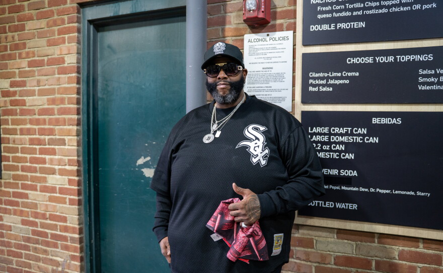 Man in White Sox shirt stands nect to sign.