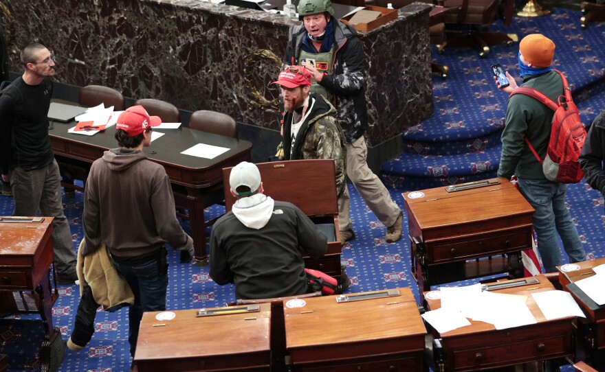 Bruno Cua is allegedly seen here with his back to the camera, holding a tan jacket. Prosecutors say he entered the Senate chamber of the U.S. Capitol on Jan. 6 with a handful of other rioters.
