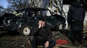 A man sits outside his destroyed building following bombings that hit the eastern Ukraine town of Chuhuiv on Thursday as Russian armed forces are trying to invade Ukraine from several directions, the border guard service said.