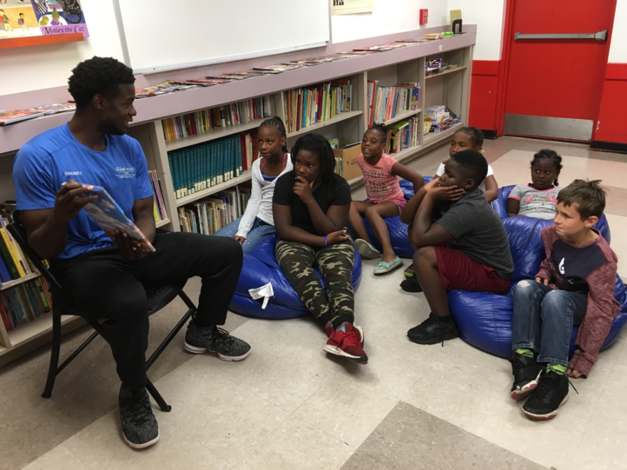 Chauncy Walker, a recreational aide at Porters Community Center, reads “Ron’s Big Mission” to children participating in the reading program. (Catie Wegman/WUFT News)