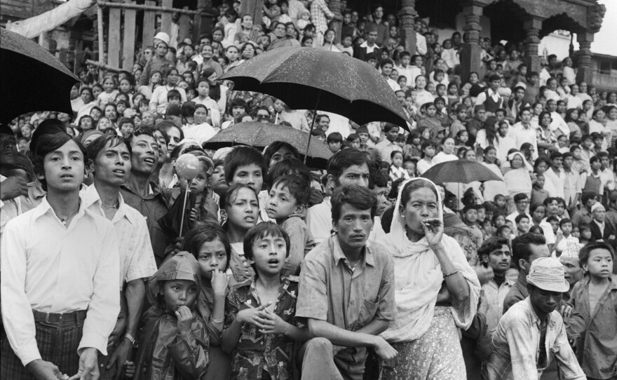 A monsoon rain doesn't deter the devout from witnessing a chariot ride by a young girl worshipped as a living goddess known as Kumari — derived from the word for "virgin." Kathmandu, 1975.