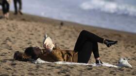 A woman reads a book at the beach. (Manu Fernandez/AP)