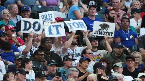 Fans wave signs for "Jimothy," a raccoon in a viral video from Seattle, during a baseball game between the Seattle Mariners and the Cincinnati Reds, Tuesday, July 21, 2026, in Seattle. 
