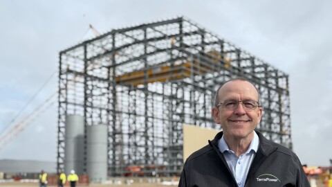 A man stands for a photo in front of a building made of scaffolding.