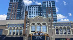 A high rise building towers over an Ann Arbor landmark, the Michigan Theater