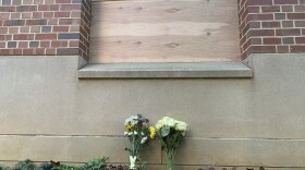 Flowers lay under a boarded up window at Caudill Labs on the UNC-Chapel Hill campus in Chapel Hill, N.C., Tuesday, Aug. 29, 2023, after a graduate student fatally shot his faculty adviser. A bullet hole could be seen earlier Tuesday in the bottom left corner of that window.