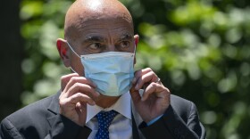 Moncef Slaoui, chief scientific adviser for Operation Warp Speed, listens as President Trump delivers remarks about coronavirus vaccine development in the Rose Garden on May 15. Slaoui says Americans could start seeing a vaccine by the middle of December.