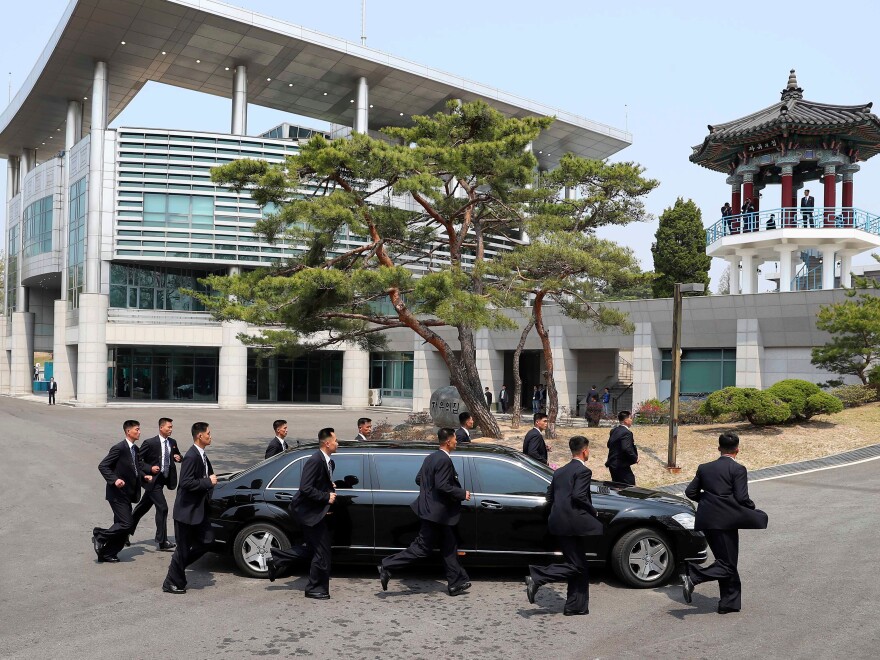 North Korean security officers jog alongside the vehicle carrying Kim as he left for a lunch break after the morning session of his summit meeting with Moon.